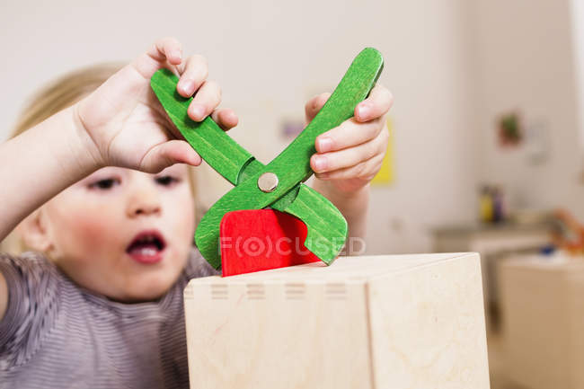 Chica jugando con alicates de juguete - foto de stock
