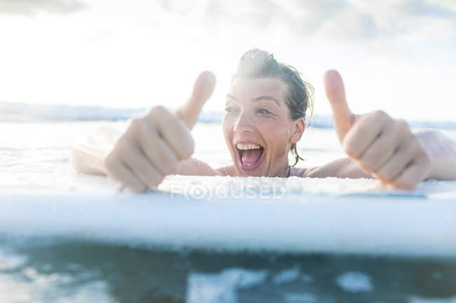 Frau mit Surfbrett im Meer gibt Daumen hoch, nosara, guanacaste provinz, costa rica — Stockfoto