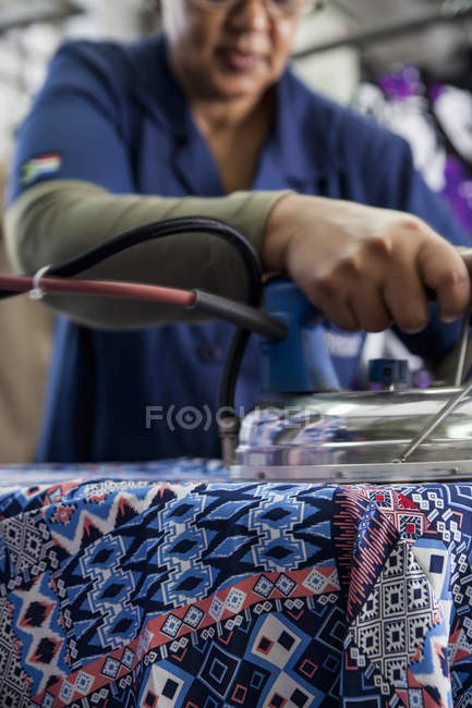 Worker ironing dress in garment factory — Stock Photo