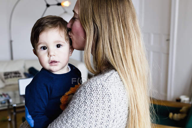 Metà donna adulta portando bambino figlio e baciando la testa — Foto stock