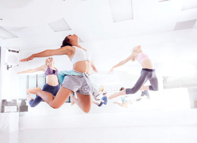 Молоді танцюристи балету, які практикують танцювальну студію, стрибають в унісон — стокове фото