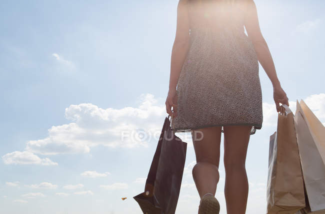 Sección media de la mujer que lleva bolsas de compras - foto de stock
