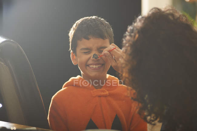 Mother painting son pumpkin nose for Halloween — Stock Photo