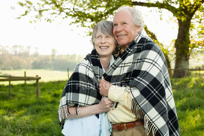 Senior couple wrapped in shawl together — Stock Photo