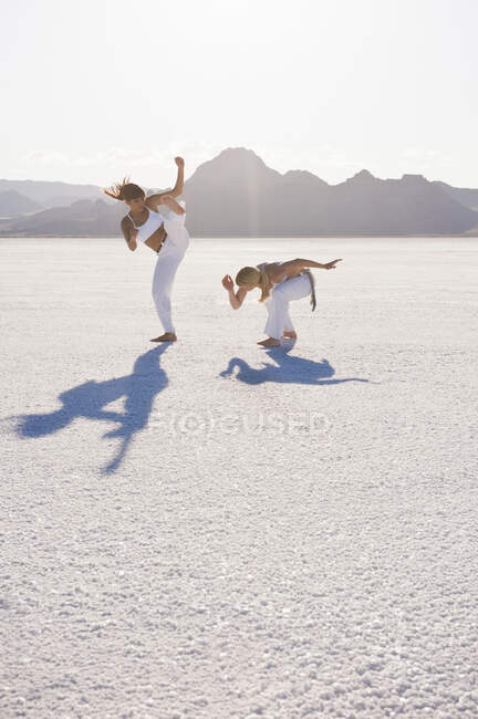 Две женщины, исполняющие капоэйру в Bonneville Salt Flats, Юта, США — стоковое фото
