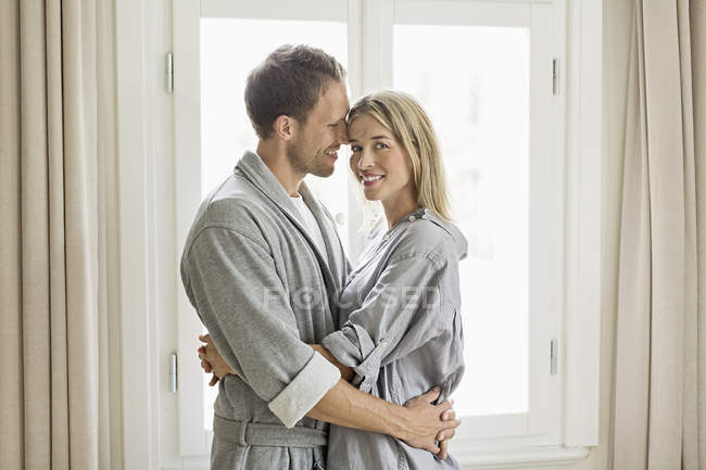 Портрет средней взрослой пары в халатах, обнимающихся — стоковое фото