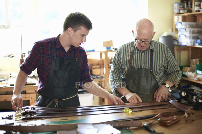 Two male workers in leather workshop, checking leather belts — Stock Photo