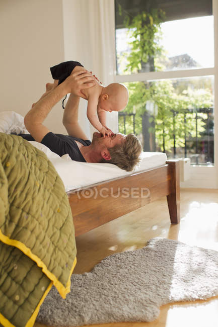Padre giocare con bambino figlia su letto — Foto stock