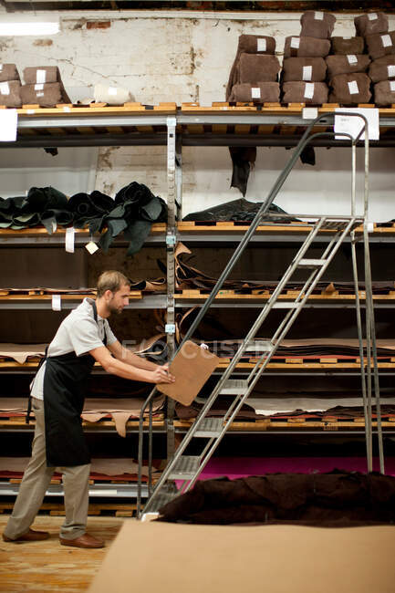 Young man working in leather stockroom — Stock Photo