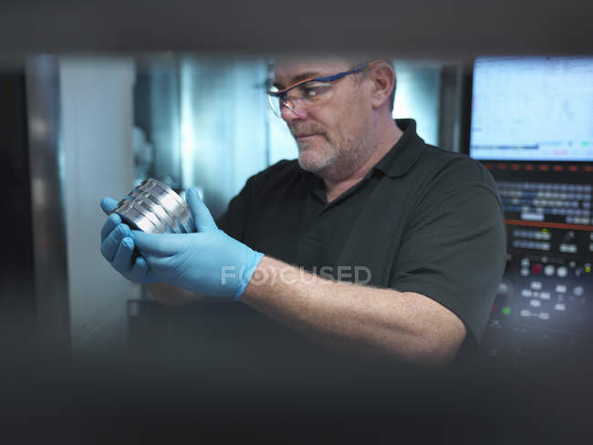 Porträt eines Ingenieurs, der ein technisches Teil an einer CNC-Maschine in der Fabrik hält — Stockfoto