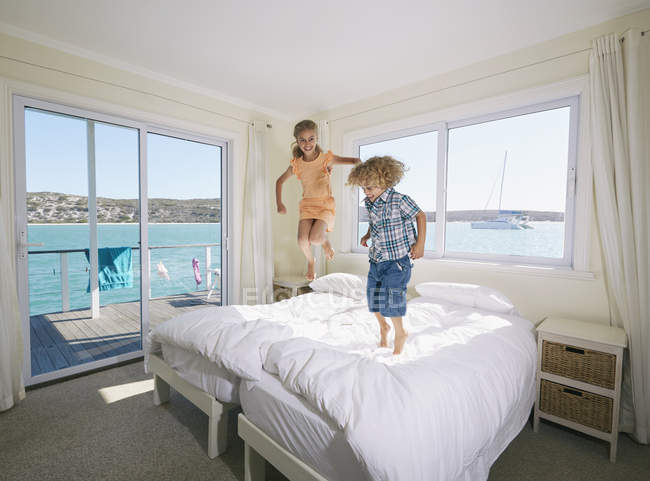 Boy and girl jumping on bed in houseboat, Kraalbaai, South Africa — Stock Photo