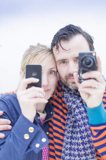 Couple taking photos with smartphone and camera outdoors — Stock Photo