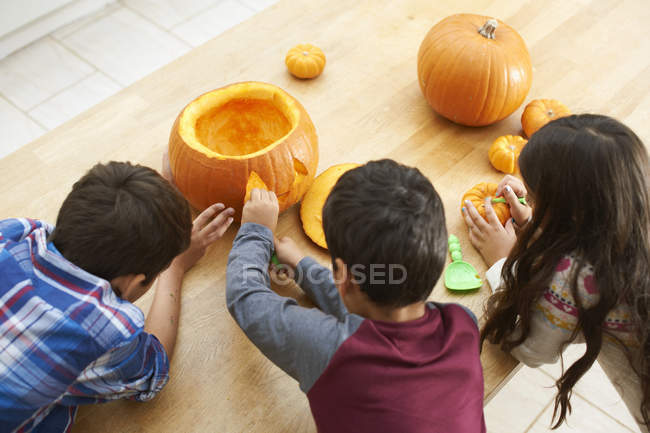 Siblings carving pumpkins in dining room — Stock Photo