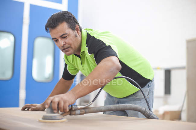 Homem lixando prancha de madeira na oficina carpinteiros — Fotografia de Stock