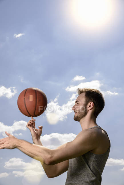 Jeune joueur de basket-ball mâle tournant la balle sur le doigt — Photo de stock