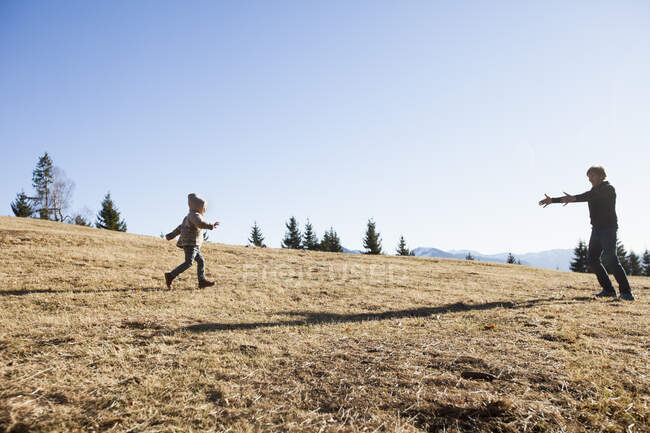 Criança feminina correndo para o pai na colina, Tegernsee, Baviera, Alemanha — Fotografia de Stock