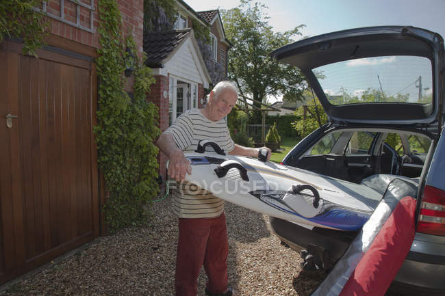 Homem sênior removendo a prancha de surf da bota do carro — Fotografia de Stock