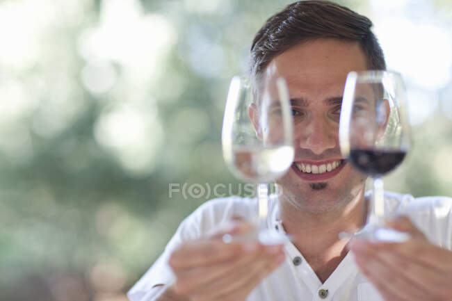 Jovem garçom masculino segurando copos de vinhos tintos e brancos — Fotografia de Stock