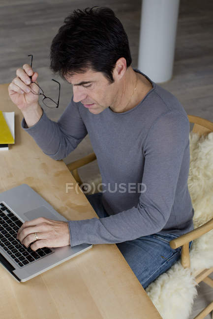 Зрелый бизнесмен работает с ноутбуком дома — стоковое фото