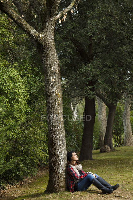 Adolescente sentada contra a árvore na floresta — Fotografia de Stock