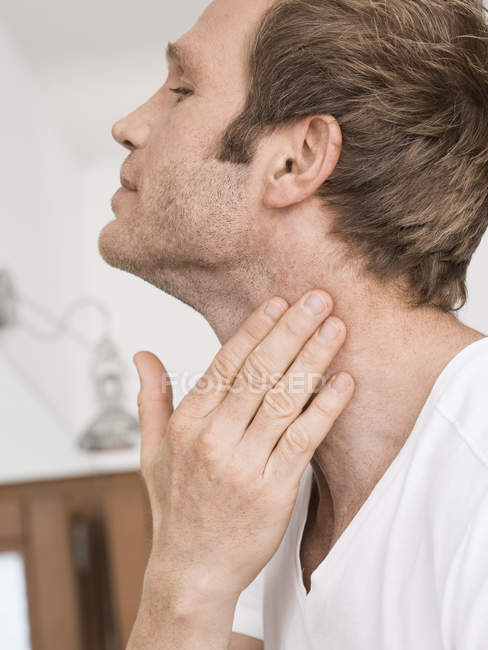 Close up of man in bathroom applying moisturizer to neck — Stock Photo