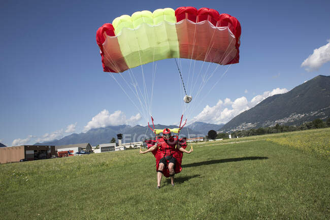 Paracadute di atterraggio Skydiver sul campo. Guidare e rallentare il suo baldacchino tirando interruttori di pausa, Locarno, Tessin, Svizzera — Foto stock