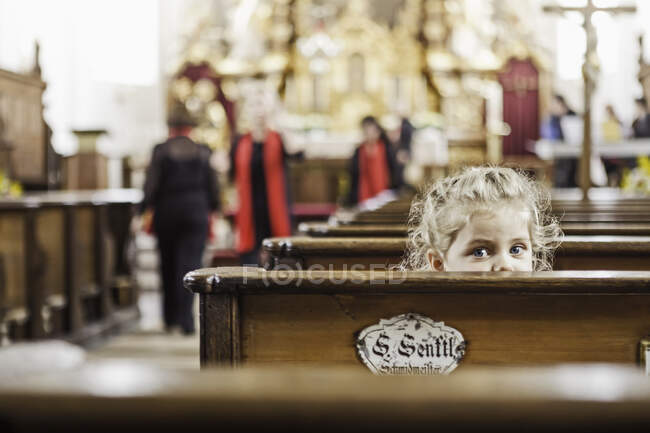 Ritratto di bambina che sbircia sopra la panche della chiesa — Foto stock