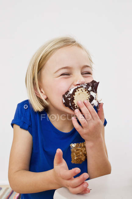Studio portrait of young girl eating chocolate marshmallow — cauca, white  background - Stock Photo | #167999174