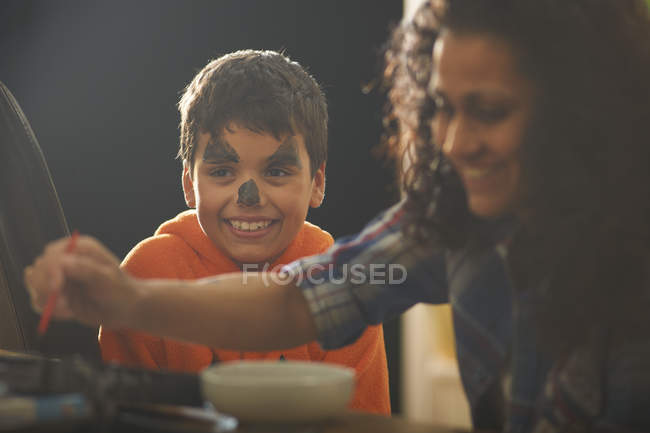 Mother painting son pumpkin face for halloween — Stock Photo