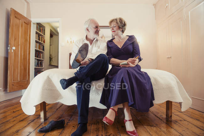 Paar sitzt auf dem Bett, Mann zieht Schuhe an und schaut Frau an — Stockfoto