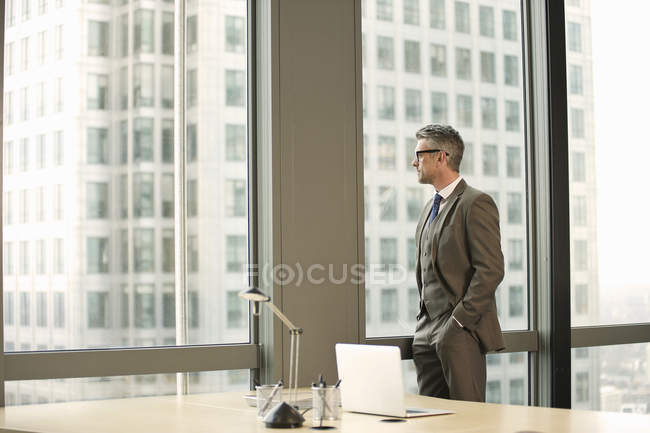 Businessman looking out of office window — Stock Photo