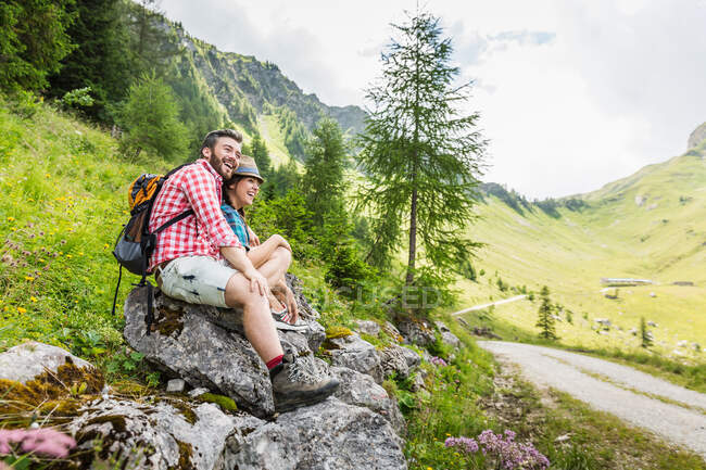 Parejas jóvenes sentadas en las rocas, Tirol, Austria - foto de stock