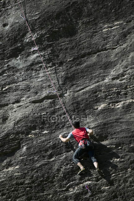 Escalador escalando roca cara - foto de stock