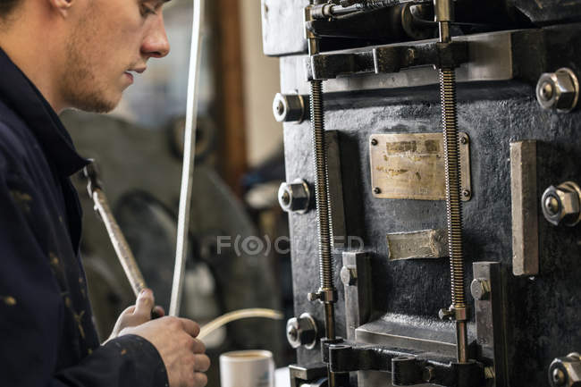 Young male printer operating printing machinery in printing press workshop — Stock Photo
