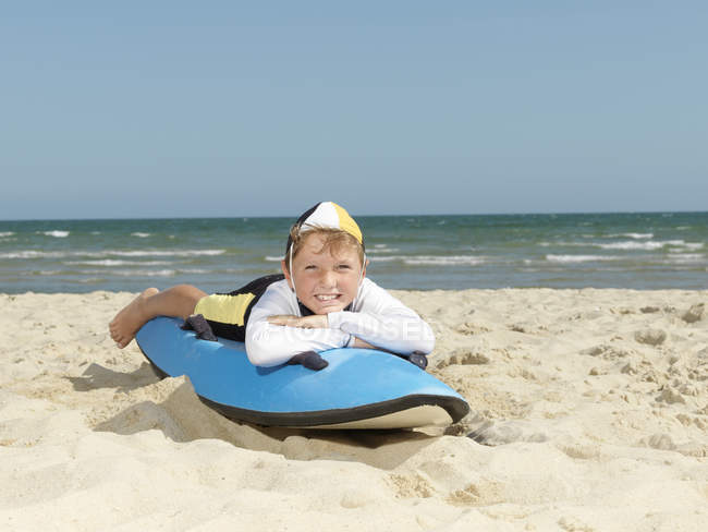 Portrait of boy nipper (child surf life savers) lying on surfboard at beach, Altona, Melbourne, Australia — Stock Photo
