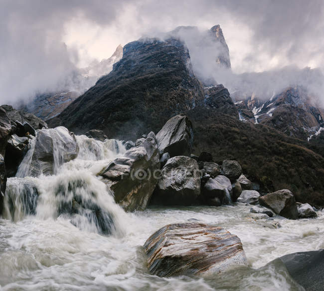 Movimiento agua borrosa que fluye por las rocas brumosas - foto de stock