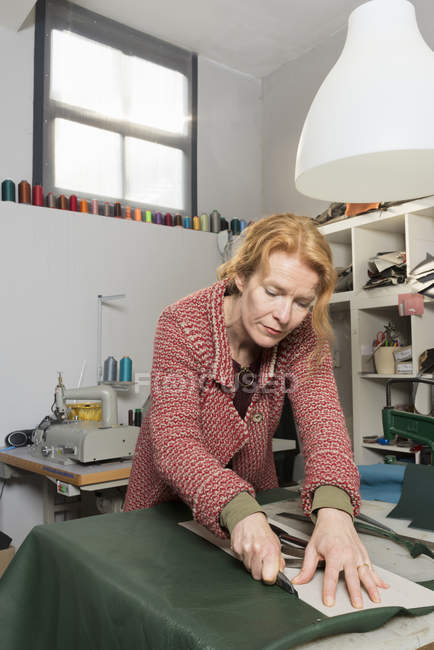 Woman in workshop trimming leather skin — Stock Photo
