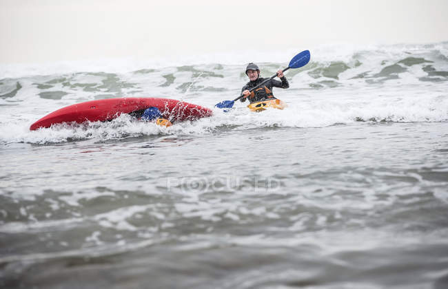 Homem maduro resgatando pessoa caída no mar em caiaque — Fotografia de Stock