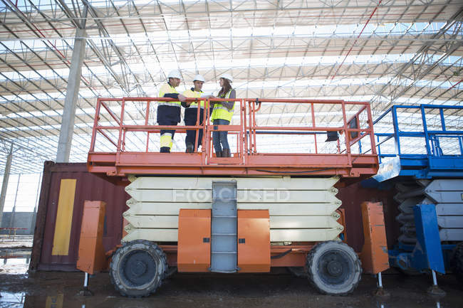 Low angle view of site managers and architect on viewing platform on construction site — Stock Photo