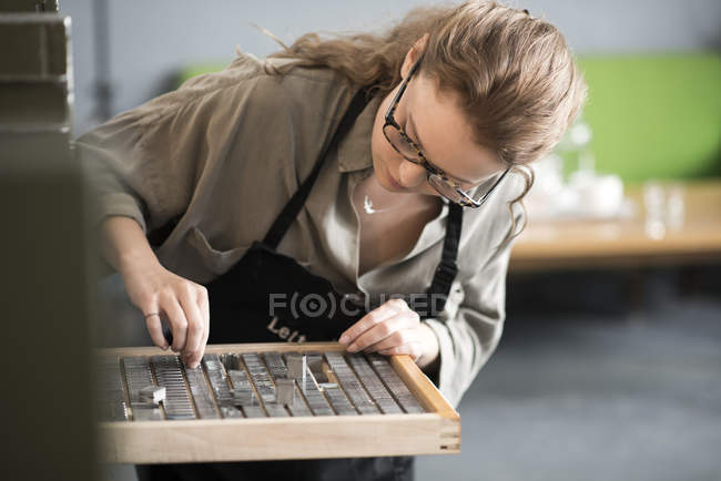 Frau wählt in Druckereiwerkstatt Buchdruck aus Tablett — Stockfoto