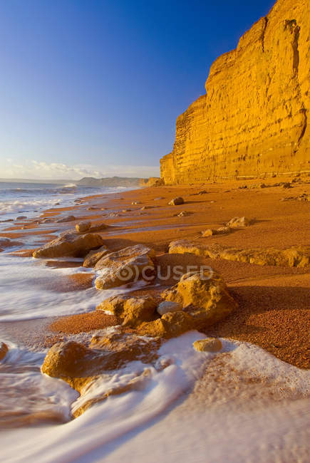 Ondas lavándose en la playa de arena - foto de stock