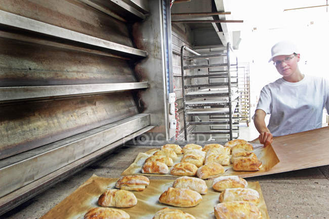 Baker putting bread onto baking sheet — Stock Photo
