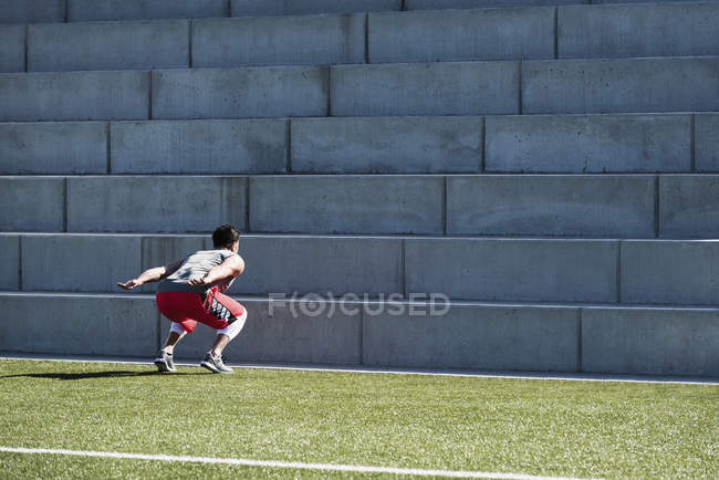 Young man training, preparing to jump up playing field stairway — Stock Photo