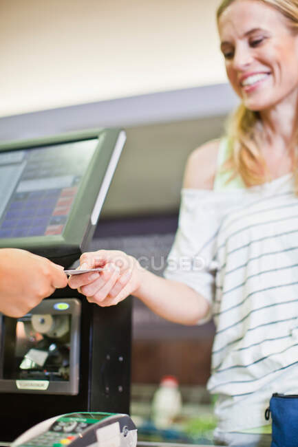 Femme payant avec carte de crédit en magasin — Photo de stock