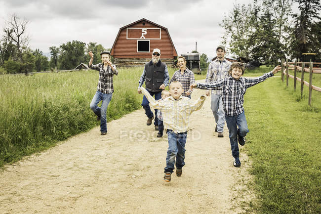 Jungen, die auf Feldwegen laufen, die Arme erhoben und lächelnd in die Kamera schauen — Stockfoto