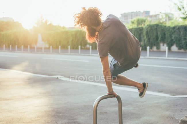 Young male hipster kicking up heels on sunlit sidewalk — Stock Photo