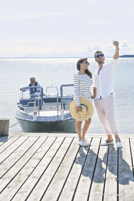 Couple photographing themselves on pier, Gavle, Sweden — Stock Photo