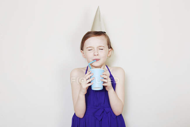 Дівчинка п'є з пластикової чашки з соломою. — стокове фото