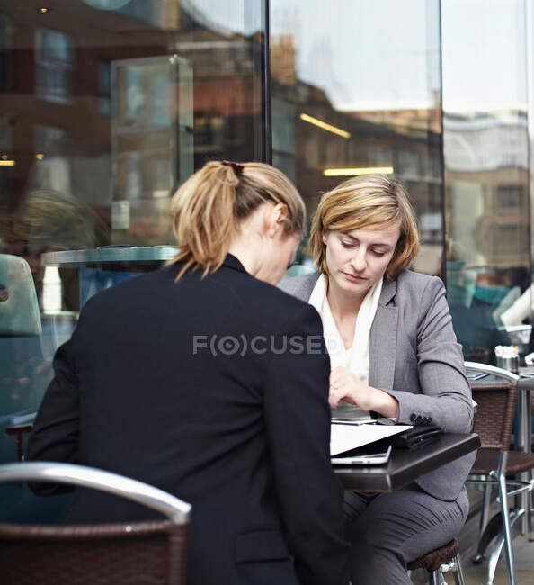 Dos mujeres de negocios se reúnen en la cafetería al aire libre - foto de stock