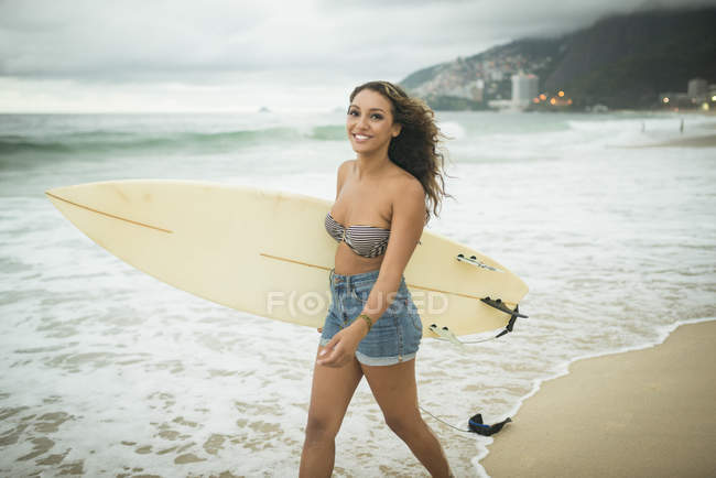 Молода жінка з дошкою для серфінгу на пляжі — стокове фото